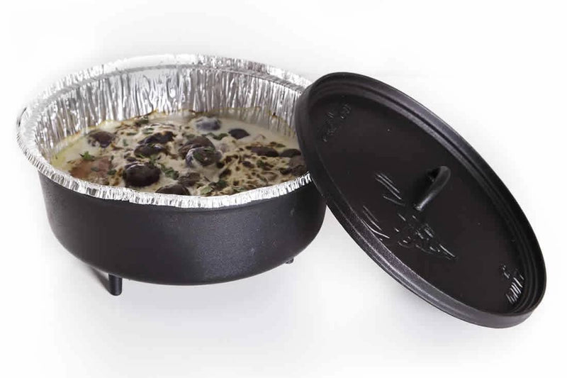Load image into Gallery viewer, A black cast iron Dutch oven holds a foil-lined dish, possibly using Camp Chef Disposable Dutch Oven Liners, topped with black olives. The lid rests beside the pot on a white background—ideal for Dutch oven cooking.

