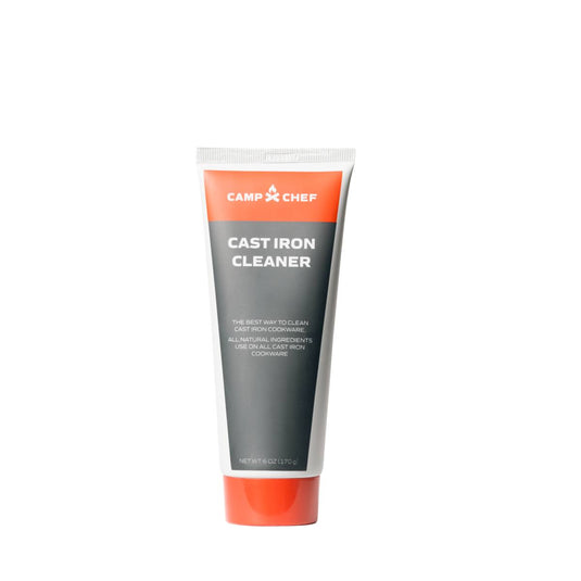 A tube of Camp Chef Cast Iron Cleaner, featuring a gray and orange design, stands upright on a white background. Its label indicates it uses natural oils and effective agents to clean cast iron cookware.