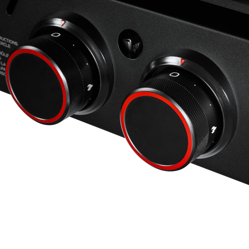 Load image into Gallery viewer, Close-up of two black control knobs with red accents on the Camp Chef Gridiron Gameday outdoor cooking system. The knobs have white indicator markings and symbols, set against a sleek black surface.
