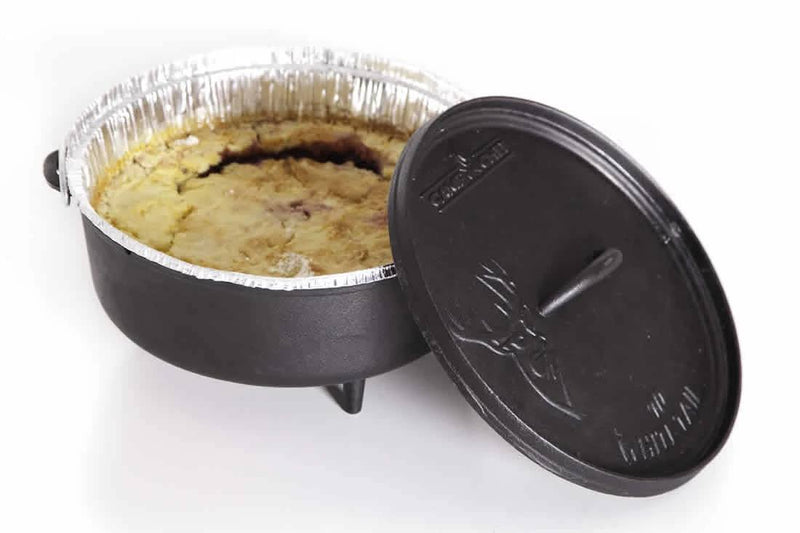 Load image into Gallery viewer, A Camp Chef Disposable Dutch Oven Liner lines a round foil baking dish filled with cobbler, nestled in a black deep Dutch oven with its lid partially open—making Dutch oven cooking easy and mess-free.
