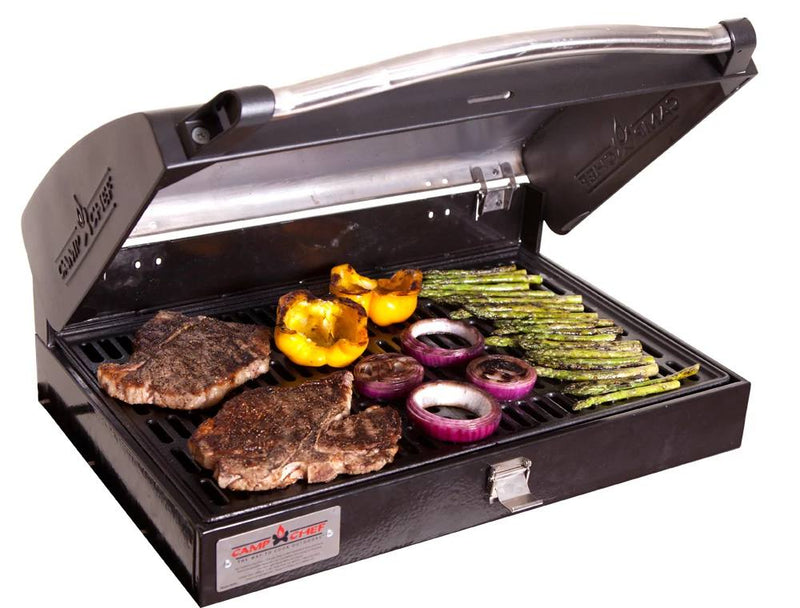 Load image into Gallery viewer, The Camp Chef BBQ Grill Boxes 16 features cast iron grates, shown here with the lid partially open while grilling two steaks, yellow bell pepper halves, sliced red onions, and asparagus spears to perfection.
