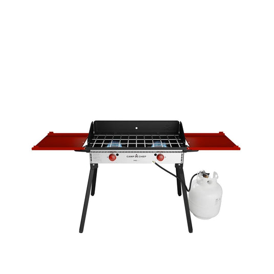 The Camp Chef PRO 14 is a portable propane gas grill with red side shelves, black legs, and an attached white propane tank, ideal for outdoor cooking and compatible with the Camp Chef cooking system. Shown on a white background.