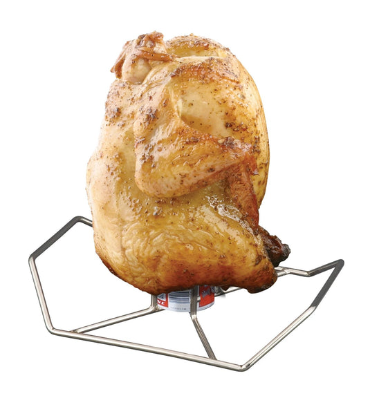 A whole roasted chicken stands upright on the Camp Chef Beer Can Chicken Holder atop a grill, its skin browned and crispy—a testament to the flavorful beer can chicken cooking technique.