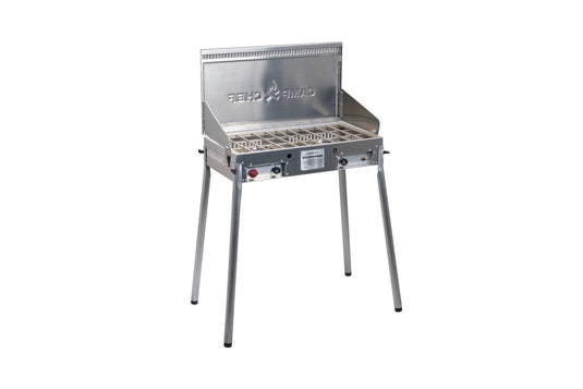The Camp Chef Mountaineer is a silver, freestanding outdoor cooking system with four legs, wire cooking grate, side and back panels, control knobs, and a front label.
