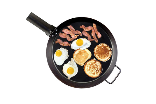 The Camp Chef Lumberjack Skillet - 16” can hold three sunny-side-up eggs, three pancakes, and several strips of bacon, all displayed on a white background.