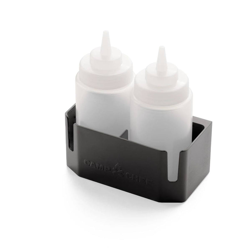 Load image into Gallery viewer, Two clear squeeze bottles with white caps sit upright in a black Bottle Caddy bottle holder by Camp Chef, embossed with the brand name on the side. The holder features an open front and is set against a white background.
