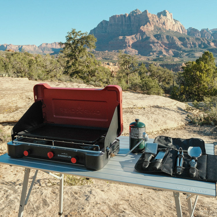 Camp stove on a table with a mountainous landscape in the background