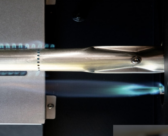 Close-up of a metallic object with a glowing blue flame on a dark background
