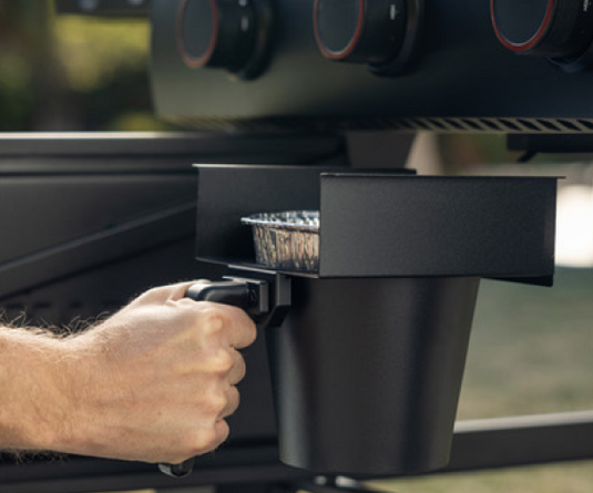 Person using a coffee maker on a grill with a blurred background