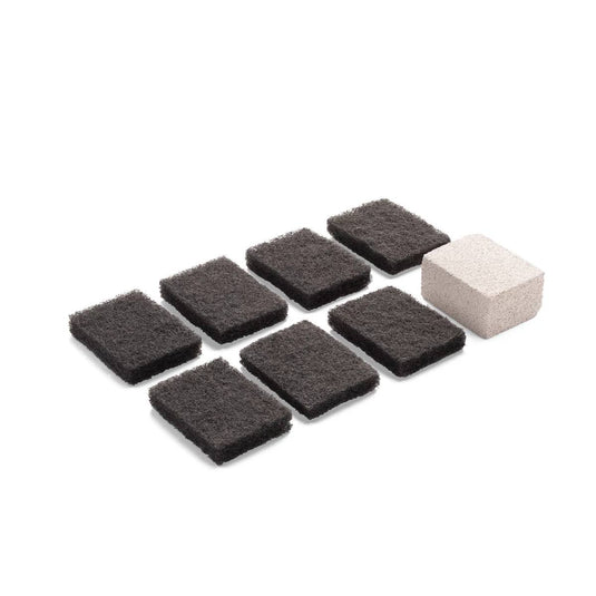 Nine rectangular Camp Chef Replacement Scouring Pads are arranged in rows next to a single light-colored pumice stone, all displayed on a white background.