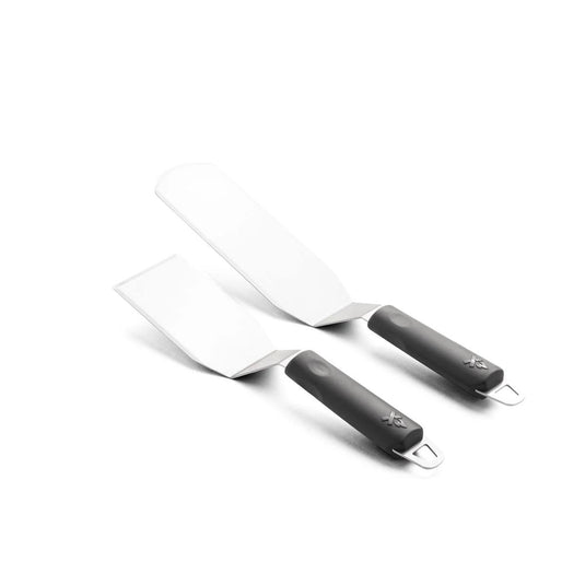 The Camp Chef Spatula Set features two metal spatulas with black handles and silver hanging loops on a white background. The set includes one larger flat top spatula; both have flat, angled blades for versatile kitchen use.