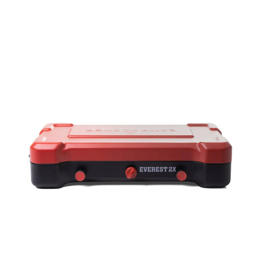 A red and black rectangular Camp Chef Everest 2X camping stove with two burners, two control knobs, a central ignition knob, and branding, displayed on a white background.