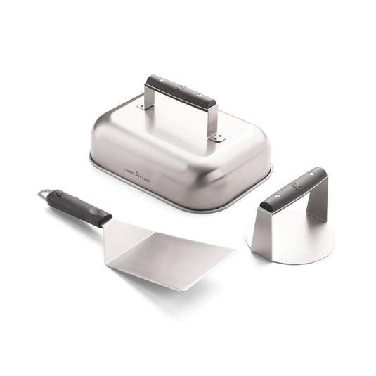 The Camp Chef Smashed Burger Kit includes three stainless steel tools: a rectangular melting dome with handle, black-handled burger spatula, and a round meat press—all in a modern brushed metal finish.