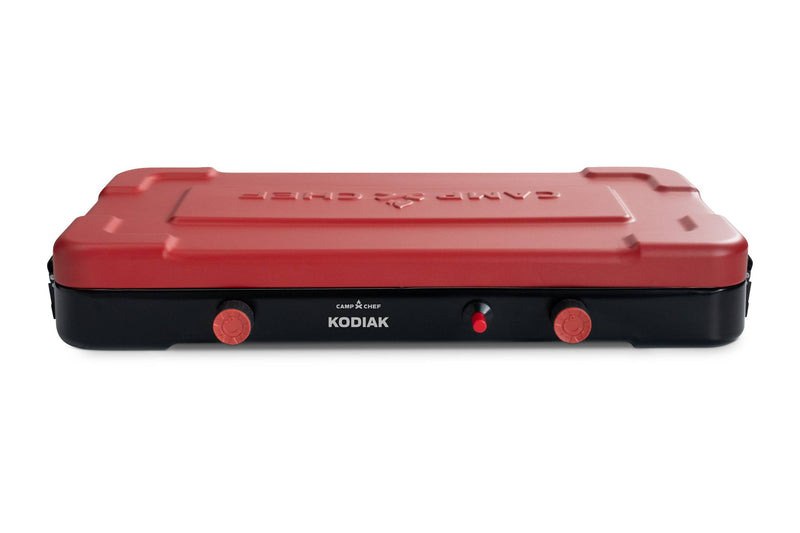 Load image into Gallery viewer, The Camp Chef Kodiak is a portable camp stove with a red lid, black base, two control knobs, and a central ignition button on the front panel.
