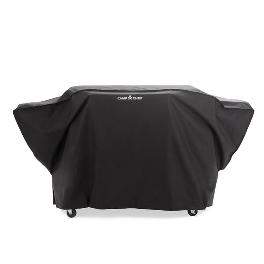 A large flat top grill sits outdoors, protected by the Camp Chef Gridiron 36 Patio Cover; most patio gear stays hidden beneath, with just the wheels visible below.