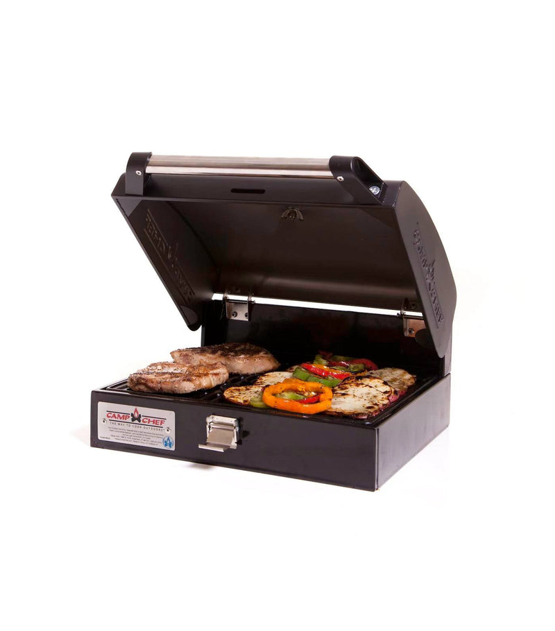 Load image into Gallery viewer, With its lid open, the Camp Chef BBQ Grill Boxes 14 cooks steaks, peppers, zucchini, and mushrooms on a cast iron surface. This compact black grill is perfect for at-home or outdoor use and sits on a white background.
