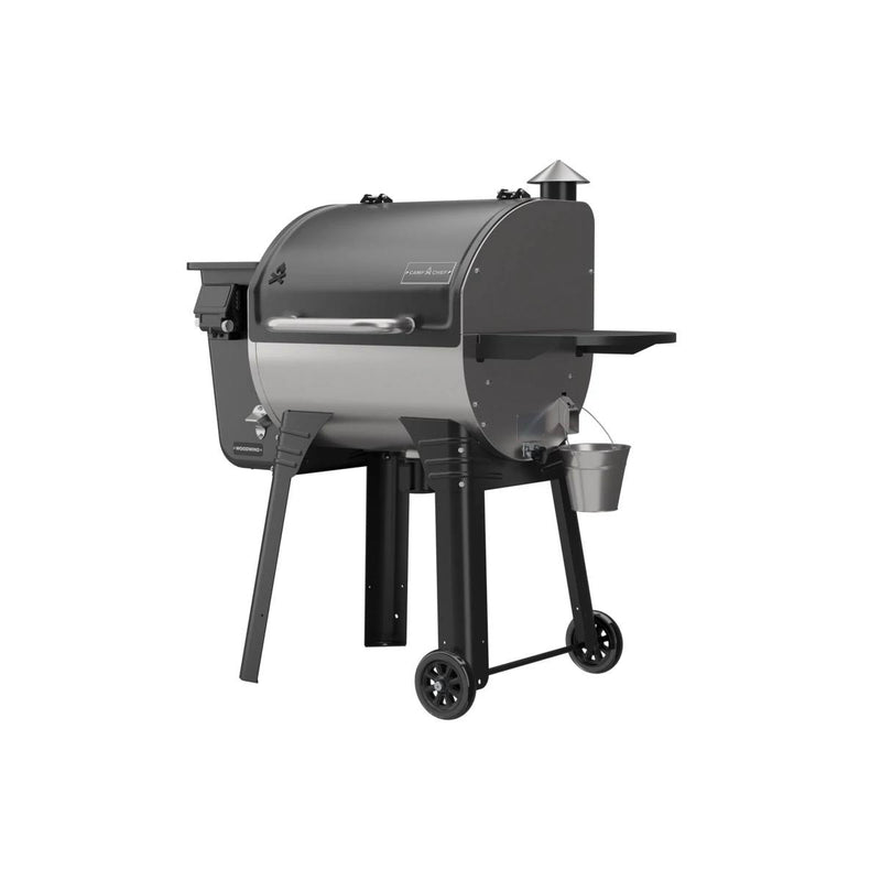 Load image into Gallery viewer, The Camp Chef Woodwind 24 is a black and silver, barrel-shaped pellet grill smoker featuring WIFI control, a chimney, side shelf, wheels for mobility, and a small metal bucket underneath for grease collection.
