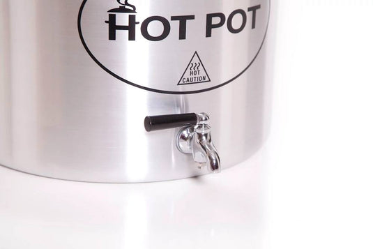 Close-up of the Camp Chef Hot Water Pot, a stainless steel outdoor dispenser with a black-handled spigot and labeled 