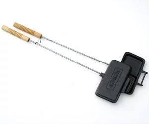 The Camp Chef Dual Square Cooking Iron features a rectangular hinged cast iron compartment and two wooden handles, shown open on a white background—ideal for classic campfire cooking.