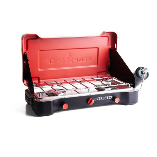 The Camp Chef Everest 2X is a portable 2-burner camping stove with a red lid, black base, control knobs, open-top burners, and a right-side propane attachment—ideal for outdoor cooking.